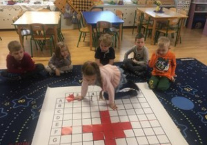 dzieci siedzą przy macie do kodowania i układają serce z czerwonych kartoników